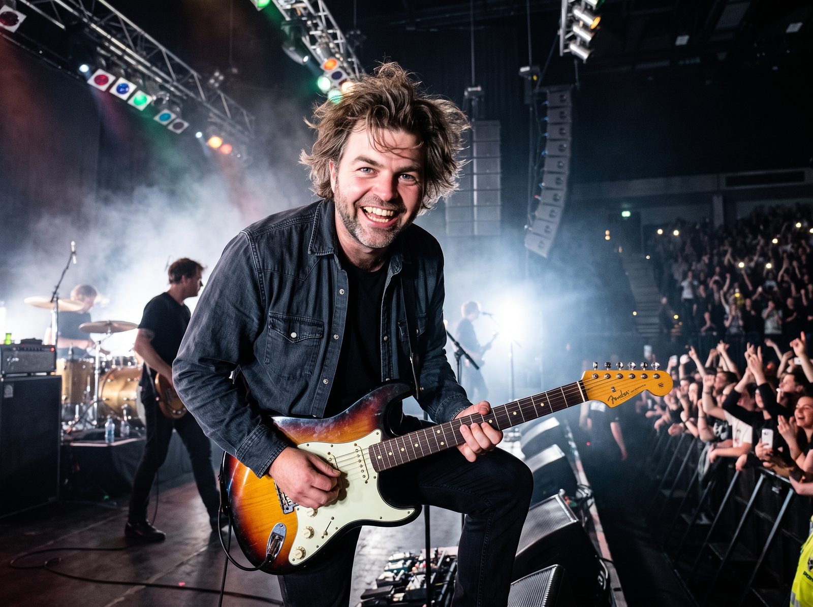 Guitarist på scenen foran et fyldt publikum